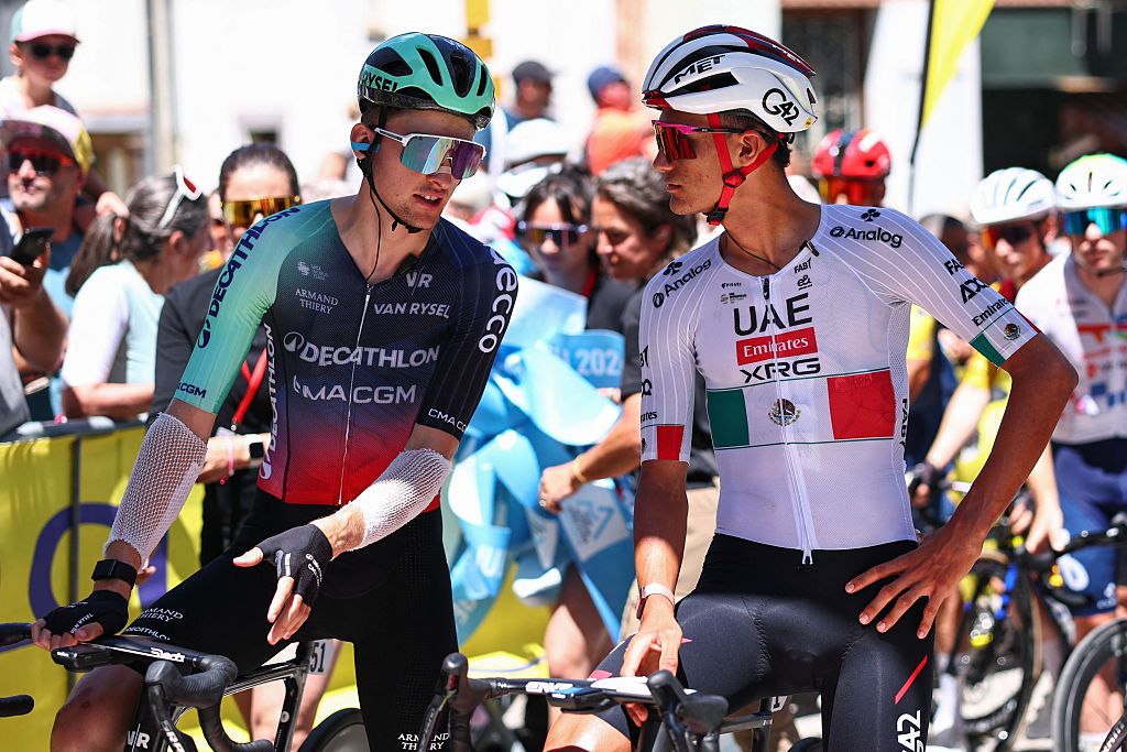 Paul Seixas (L) and Isaac Del Toro Romero speak at the start line before the 8th and final stage of the Tour Auvergne-Rhone-Alpes